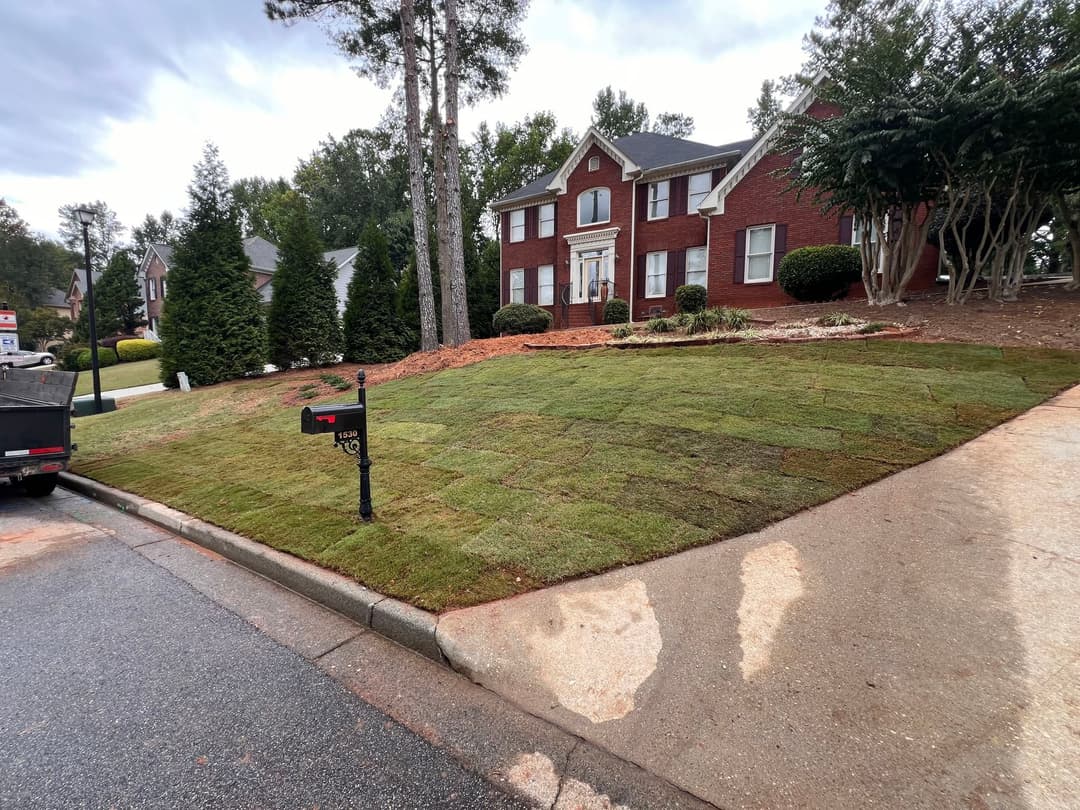 Lush green lawn and brick house with well-kept landscaping on a quiet street.